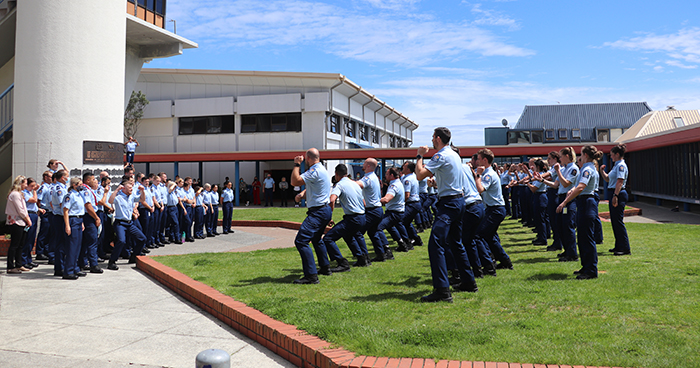 Wing 347 stand in front of the Memorial Wall before their graduation while members of Wings 348 and 349 honour them with the Police haka.