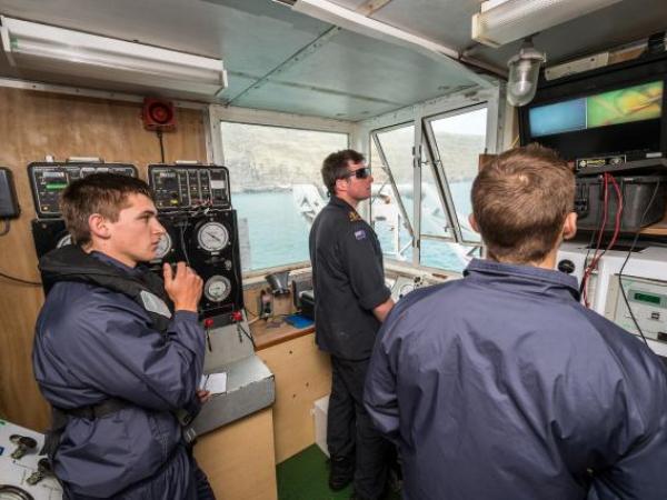 Members of the Royal New Zealand Navy Operational Dive Team monitor divers in the water from the 'Dive Shack' on HMNZS MANAWANUI