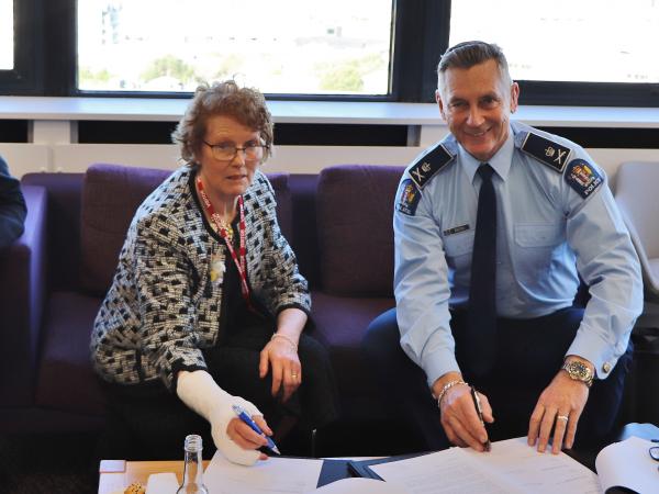 Lesley Elliott signs over the foundation's work to Commissioner MIke Bush, watched by trustee Bill O'Brien.