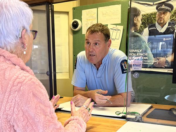 Senior Constable Paul Hampton talking to someone at the front desk. 